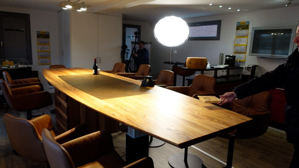 Der Raclette-Käse wird auf den Sitz-Stehtisch aus Massivholz geworfen