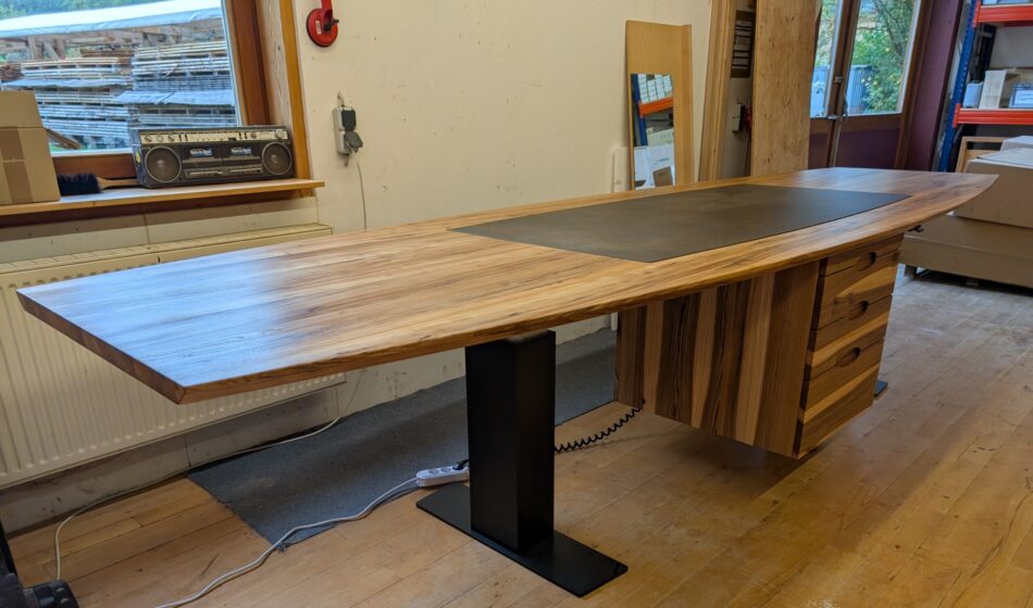 Der Konferenztisch oder Sitz-Steh-Konferenztisch ist elektrisch höhenverstellbar und unter der Karmikplatte ist ein Induktionskochfeld montiert